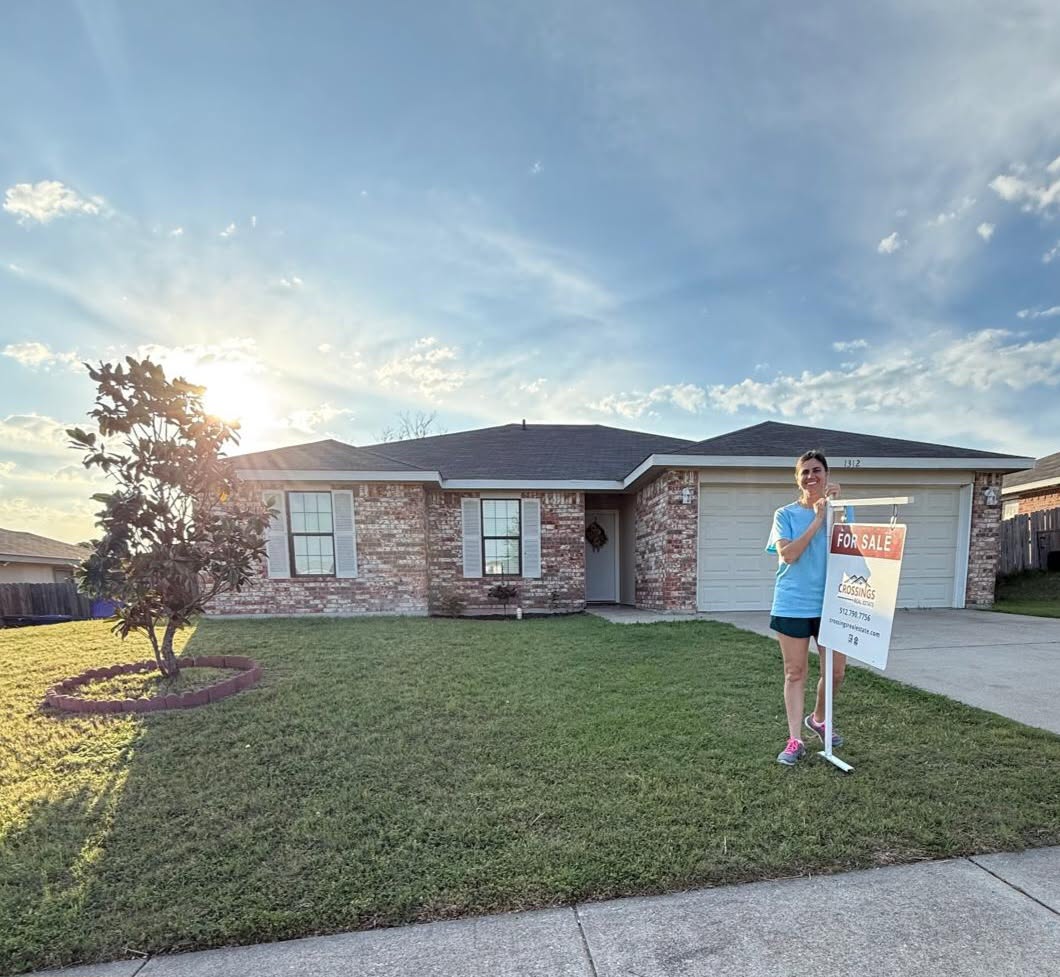 Ashley Billins standing by a For Sale sign in front of a home she listed